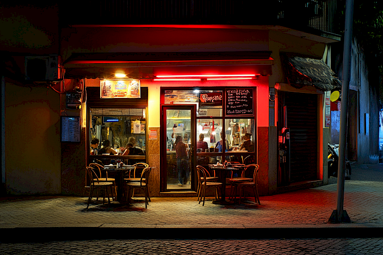 Fachada de cafeteria iluminada à noite em rua urbana