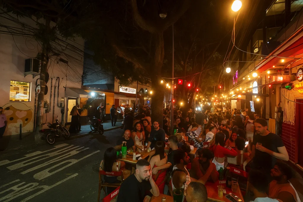 Rua com bares lotados e mesas ao ar livre durante a noite